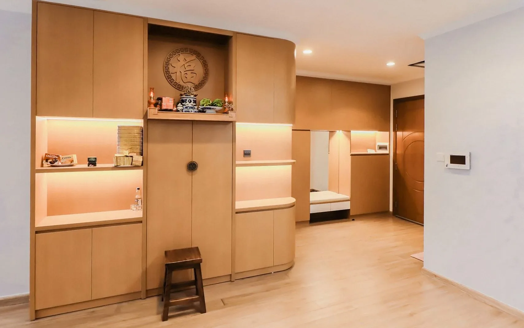 木製の造り付け収納と間接照明のある部屋に置かれたスツール